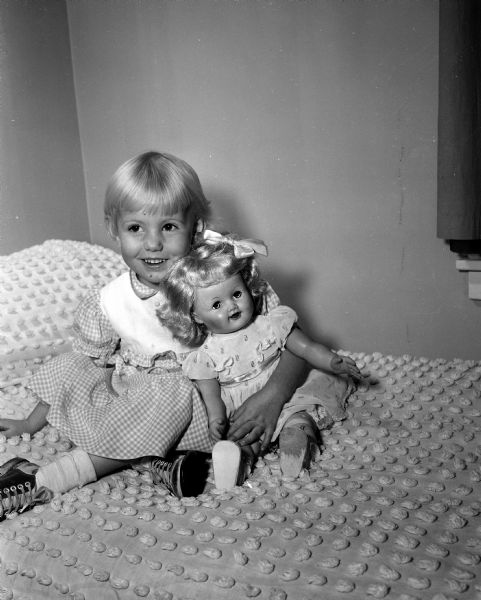 Rebecca Rae Rodgerson, age three, hugs a doll she received from the Empty Stocking Club, as imagined in Monte Allen's dream. The club, sponsored by the <i>Wisconsin State Journal</i>, raises funds for Christmas toys for needy children in the Madison area.