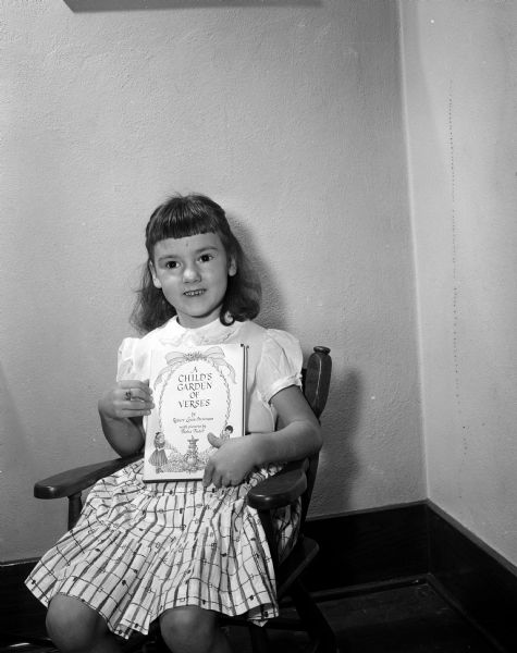 Jane Curran, age seven, posing with a book on children's poems she received from the Empty Stocking Club, as imagined in Monte Allen's dream. The club, sponsored by the <I>Wisconsin State Journal</I> newspaper, raises funds for Christmas toys for needy children in the Madison area.