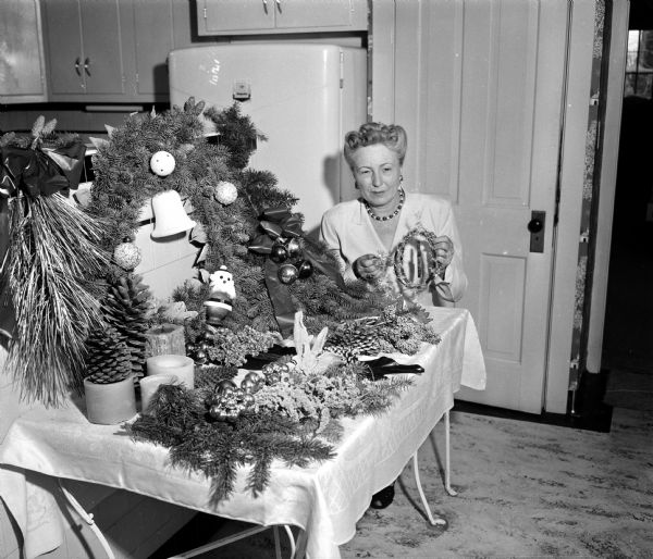 Mrs. F.D. Chamberlin displays samples of Christmas home decorations to be sold by the West Side Garden Club at their annual "Holiday House" sale.