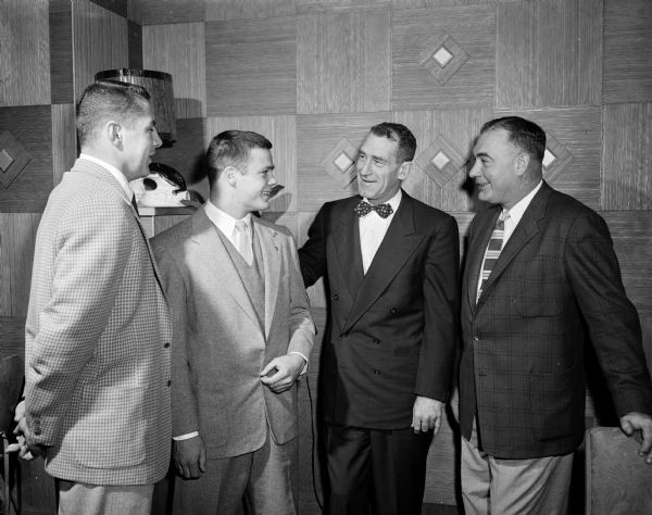 Two football players and two coaches posing at their annual banquet at Rhode's Steak House. Left to right are Wells Grey, 1955 varsity captain; Dave Munger, newly elected freshman team captain; Ivan Williamson, UW-Wisconsin head coach; and George Lanphear, freshman coach.