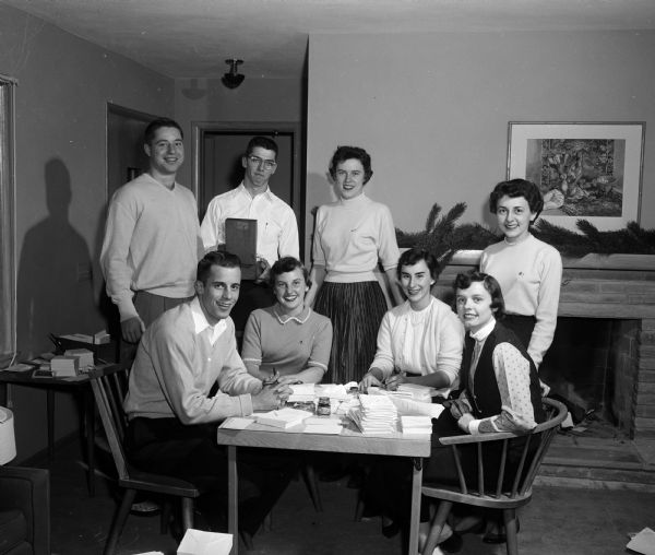 Committee members making arrangements for the Christmas Charity Ball, an event for college students and young married couples in Madison. Seated left to right: Ned Consigny, Dorothy Jones, Mrs. Theodore Crabb, Jr., and Sylvia Sachtjen. Standing:  Kurt Regenberg, Charles Forsberg, Betsy Griem, and Mary Ann Hand.