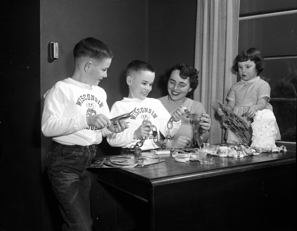 Louise Frye and her three children prepare for Christmas by making Christmas tree decorations. Left to right: Timothy, age 9; Jeffery, age 7; Louise and Ellin, age 3.