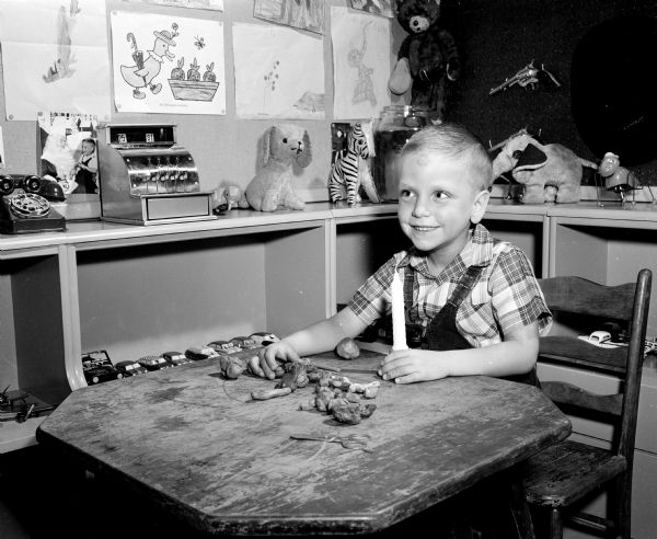 Four-year-old Tommy, son of Robert and Mary Ela, makes a candle holder from modeling clay as a Christmas gift for his mother.