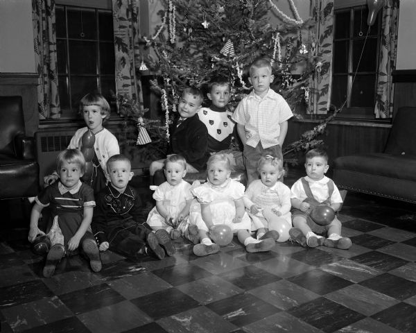 Group portrait of ten children sitting in front of a Christmas tree during a party for children of the members of the Interns and Residents Wive's Club.