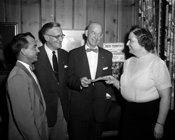 Louise Marston (right), society editor, accepts a check from three barbershop singers for the <i>Wisconsin State Journal's</i> Empty Stocking Fund. The donation is from the proceeds of a concert by the Madison chapter of the Society for the Preservation and Encouragement of Barber Shop Quartet Singing in America. Presenting the check are Roy Brumley, Calmer Browy, and Walter A. "Pat" O'Leary.
