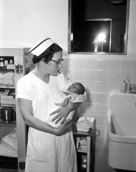 Mrs. William J. (Salome) Fix, caretaker of premature babies at St. Mary's Hospital, holds one of her tiny patients. She was diagnosed with polio in 1949.