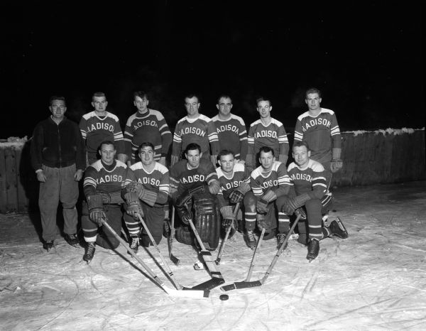 Group portrait of 13 uniformed members of the Madison Cardinals hockey team posed by a outdoor hockey rink with their pucks, hockey sticks, skates, and gear. The team hoped to regain the Fox River Valley League and state amateur championships. In the front row, from left to right, are: Bill Horstmeyer, John McCormick, Vern Wagner, Bob Soule  Ken Buss, and Orv Walsvick. In the back row, from left to right, are: coach John Riley, Marlowe Suter, Karl Bast, Manager William "Jingles" O'Brien, Chuck Warren, Penny Dittman, and Dick Wills.