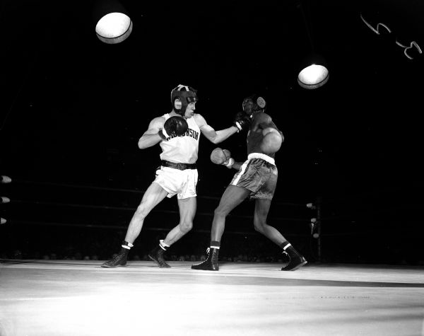 Action photo of Jim Schneider and Herb Odom (winner) during the University of Wisconsin vs. Michigan State 147-pound boxing match.