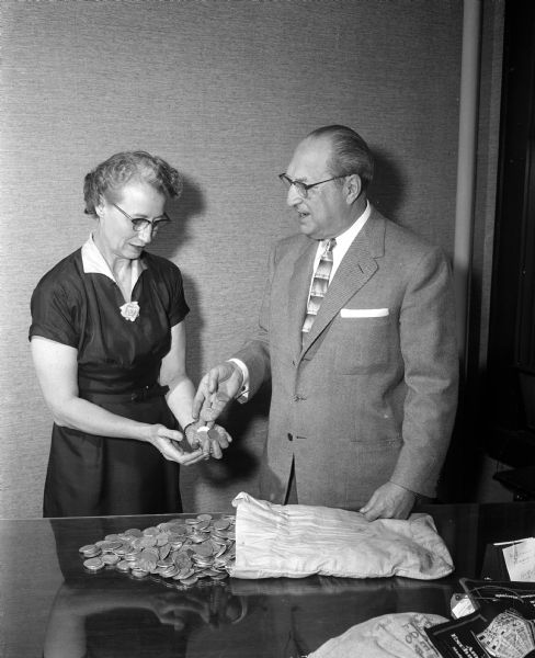Dorothy Hatfield receives a bag of silver dollars as her award from J. Jesse Hyman Sr., President of the Emporium Company, in recognition of her 13 years service with the store.