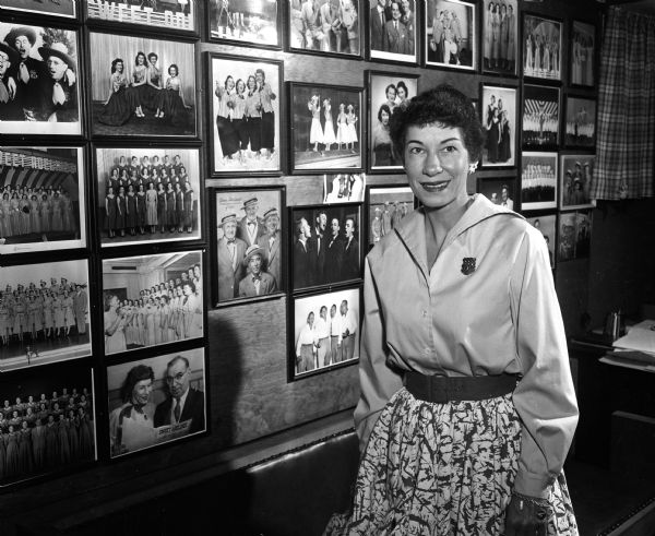 A member of the Sweet Adeline singing group poses in front of pictures of quartets.