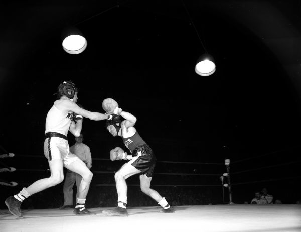 Dick Davis of Appleton (left) throws a long right at champion Frank Calarco of Milwaukee during their bout during the boxing Tournament of Contenders at the University of Wisconsin-Madison Field House. Calarco won the match and championship at 132 pounds.
