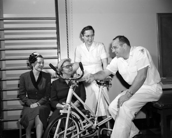 Portrait of a police officer and three ladies with an exercise bicycle at Washington School.