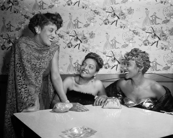 Comparing notes on the activities of the Royalettes and Royalites are Mrs. Pearl Cobb, Chicago; Mrs. Mary Cooper (Grimes), President of the Madison group; and Mrs. Audrey Hilton, Chicago. They are at a cocktail and supper party in the Gold Room of the Playdium put on by the Madison Royalettes, an African American social and philanthropic club.