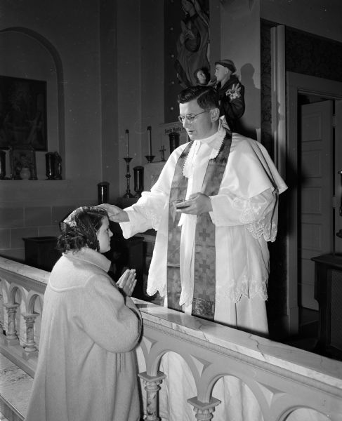 Reverend Edmund Kinate of St. Joseph's Catholic Church gives ashes to Joan Licari, eighth grade pupil in his parish school, in preparation for the Lenten observance.