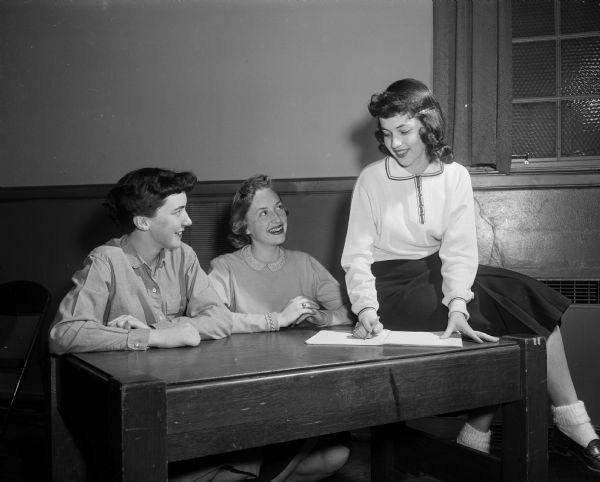 Three officers of the Junior Catholic League, composed of girls from the Madison high schools, sit around a table. They include, from left to right: Pat Putnam, Edgewood; Rita Kennedy, West, and Judy Myers, Central.