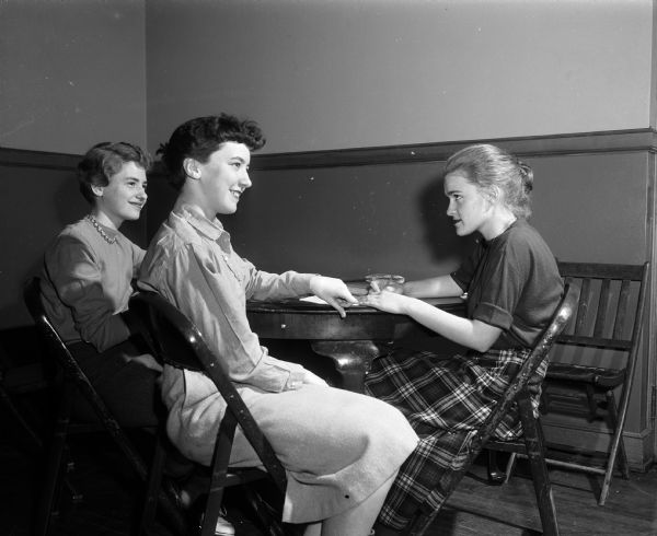 Three members of the Junior Catholic League, composed of girls from Madison high schools, meet to plan a mother and daughter tea. Left to right: Madonna Kurth, Pat Putnam, and Theresa Acker, all from East High School.