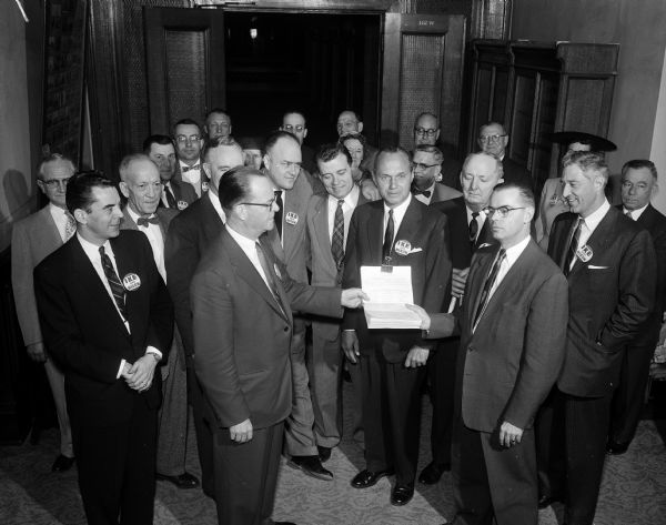 Papers containing President Eisenhower's consent to be a candidate in the Wisconsin presidential primary and the President's certified list of delegate candidates are handed by Everett Yerly, chairman of the Wisconsin Eisenhower for President Club to Gaige Roberts of the Secretary of State's office. Also pictured (left to right) are: John W. Byrnes, State Treasurer Warren Smith, Representative Melvin Laird, Representative Glenn Davis, Governor Walter Kohler, and Lt. Governor Warren Knowles, all delegates at large on the Republican slate certified by President Eisenhower.
