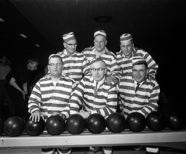 Six men in prison stripes pose with bowling balls.