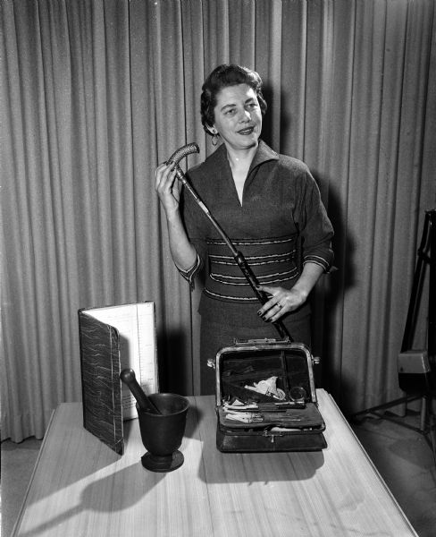 Judith Davis, president of the Dane County Medical Auxiliary, displays early Wisconsin medical equipment which is being collected for a Wisconsin Museum of Medical History at Prairie du Chien.