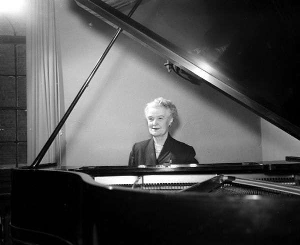 A portrait of Edith M. Davies seated at her piano.