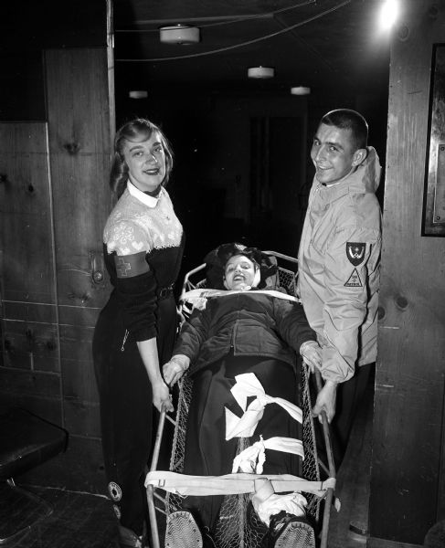 Members of the University of Wisconsin Hoofers' Ski Club demonstrate the importance of correct immobilization of fractures and proper transportation. They are, from left: Janet James, Milwaukee; Susan Edgerton, Madison; and Dennis Templar, Horicon. All members of the ski club are required to take a Red Cross first aid course before taking part in skiing activities.