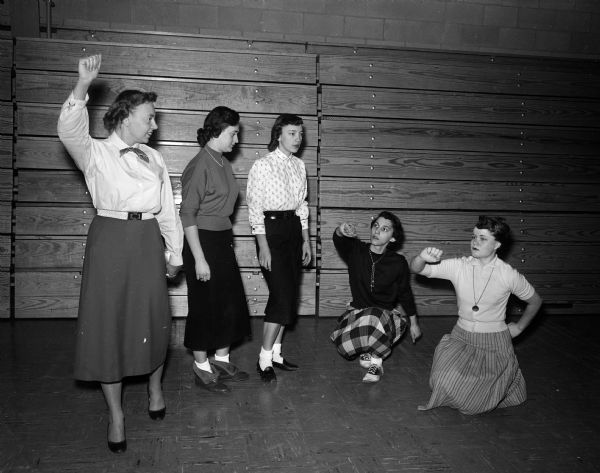 Audrey Rasmussen, faculty adviser for the Sauk City High School cheerleading corps, demonstrates proper gestures to Betty Leykauf, Jackie Kennedy, Shirley Theisen, and Karen Bongard.