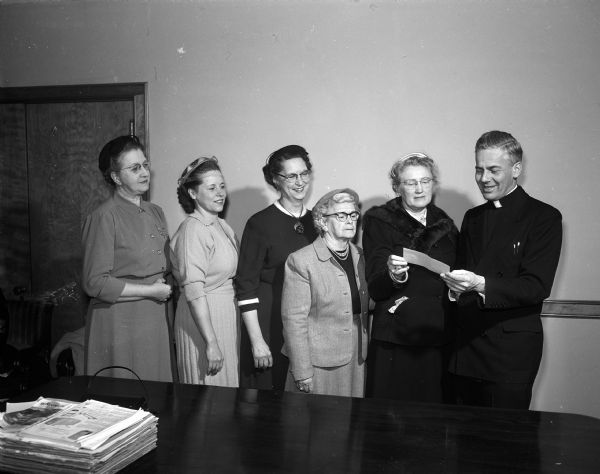 A donation to Blessed Martin House is presented to Monsignor Jerome Hastrich by members of the Women of the Moose. On left is Elsie Bostock. Others shown are: Anna Zeman, Mrs. Joseph Meyer, Anna Nelson, and Mary Gordon.