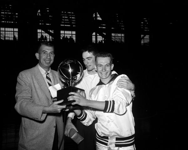 Presentation of the third place trophy for the state high school basketball tournament by University of Wisconsin basketball coach Harold E. (Bud) Foster to Sauk City players Paul Patterson (right) and Ron Hering.