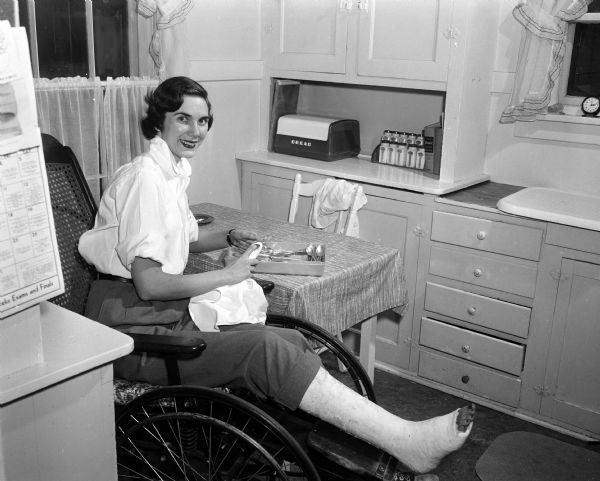 Pat Farrell, with a broken right leg, polishes silver while confined to the house she shares with three other young women at 2253 Rugby Row.