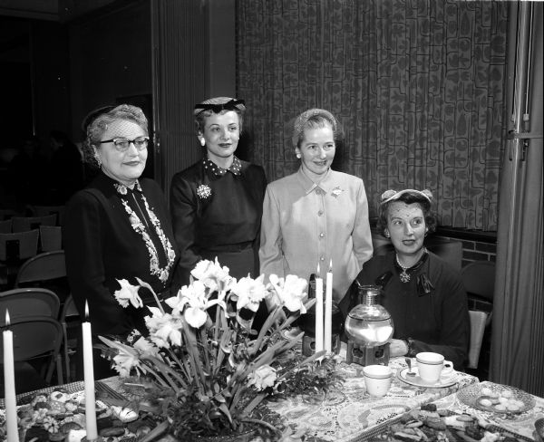 Women who poured at the tea table decorated with a floral centerpiece at an Inter-Faith Tea given by the Madison Council of United Church Women are, from left: Inez Puls, wife of the pastor of Luther Memorial church; Janet S. Pasch, Council of Jewish Women; Mrs. Roy L. Matson, St. Andrew's Episcopal Church; and Alice D. Farley, Catholic Women's Club.
