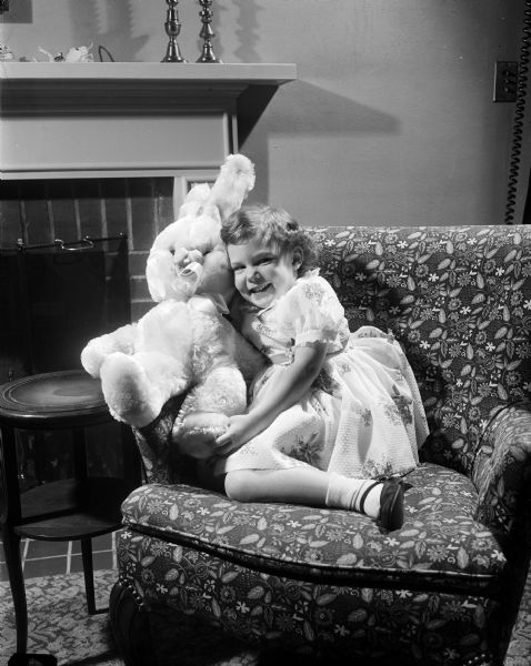 Three-year-old Jane Bush sits on a chair while hugging her pink Easter bunny.