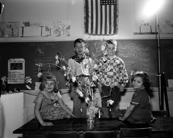 First graders of the Badger School decorated eggs and hung them on a silver tree for disabled children in the orthopedic ward of University hospitals. The four members of the class include, from left, Nancy Jo Plummer, Kenneth Kropp, Mike Adams, and Patsy Bambrough.