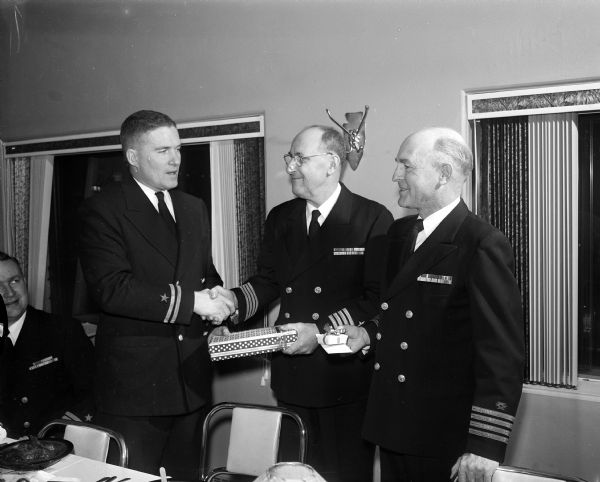 Madison's Naval Reserve Composite Company honors Captain Reed A. Rose at his retirement dinner. Capt. Rose, center, receives gifts and congratulations from Lt. William P. Gardner (left) and Capt. R.O. Lord.