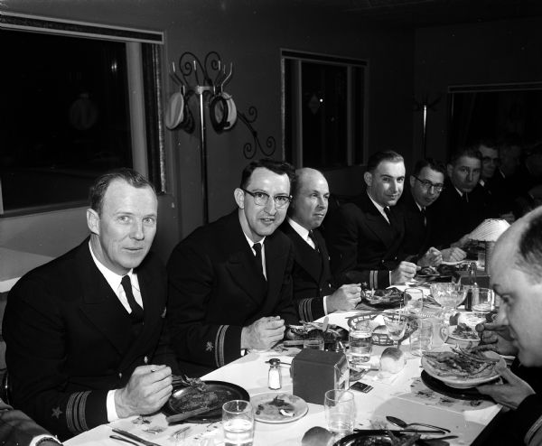 Members of the Naval Reserve Composite Company attend a retirement dinner honoring Captain Reed A. Rose. Seated left to right: Lt. Comdr. Fritz Wolf; Lt. (J.G.) Harvey Strassburger; Lt. Comdr. Harley Gibson; and Lt. A.B. Prescott. (Also shown are 5 more unidentified men, not in published version.)