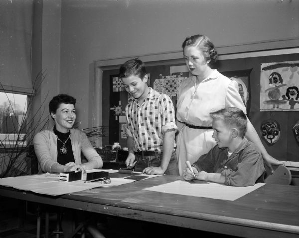 Fifth grade school students make menu covers for the Wisconsin Congress of Parents and Teachers Convention. They are seen with adults Roberta Larsen, art teacher at Sherman Elementary School, and Elaine Goff, chairman of luncheons, banquets, and locations for the event. Left to right: Roberta Larsen, Douglas Zick, Elaine Goff and William McInvaille.