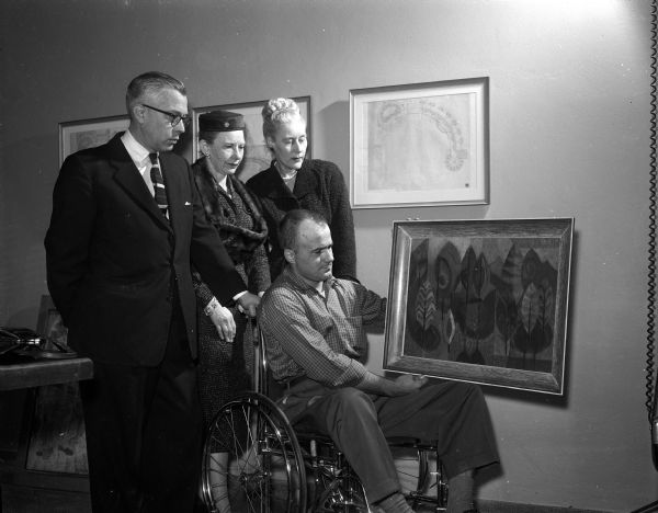 Don Eastin, Dorothy Angevine, and Louise Brown looking at a piece of artwork held by artist John Bergman that will be displayed at the Wisconsin Neurological Foundation as part of a one-man show.