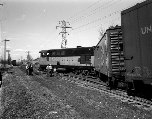 Onlookers stand near a Milwaukee Road switch engine and two boxcars derailed near the East Johnson Street crossing of the Yahara River.