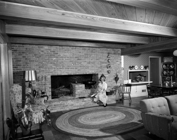 Mrs. Arthur (Bette) Sonneland, with her 19-month-old daughter Kristl, sits on the hearth of the fireplace in the family room of their home at 35 Paget Road in Maple Bluff.