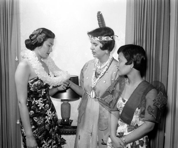 Attending the YWCA Benefit Tea for internationally speaking foreign students in costume of their native land are, left to right: Judith Ahana, Honolulu Hawaii; Ada Deer, American Indian from Keshena, Wisconsin; and Theodora Pontillas, Naga City, Philipines.
