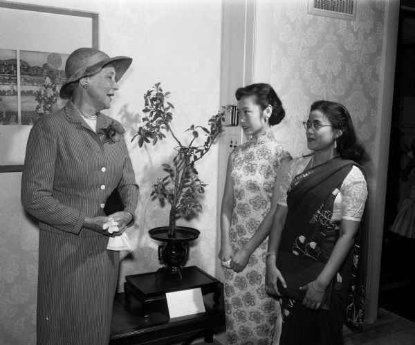 Louise Troxell, honored guest of the YWCA Benefit Tea for internationally speaking University of Wisconsin foreign students, chats with two foreign students. Left to right: Louise Troxell, retired University of Wisconsin Dean of Women; Pamela Wang, China; and Snigdna Hukerji, India. The students are dressed in costumes of their native countries.