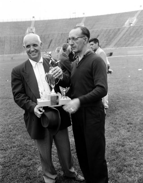 Charles Wetmore (right), president of the Wisconsin Interscholastic Athletic Association, presents the Class A trophy to Madison West High School track coach Willis Jones at the state high school track meet at Camp Randall stadium.