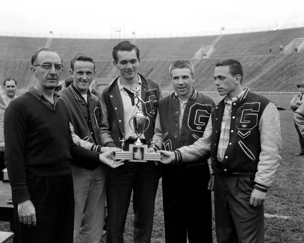 Charles Wetmore (left?), president of the Wisconsin Interscholastic Athletic Association, presents a Class B trophy to the coach and members of the Glendale High School team at the state high school track meet at Camp Randall stadium.