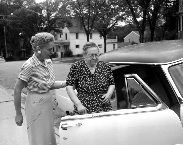 Transportation is often a problem for the older population. The Council of Jewish Women has arranged a transportation group to take older Jewish persons to activities. Estelle Black of the Council of Jewish Women is assisting Pauline Rubin into her car. Pauline Rubin likes to attend the semi-monthly meetings of the Golden Age Club at the Congregation Adas Jeshurun.