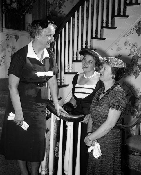 Three officers of the new Women's Committee of the Madison Civic Music Association standing in a stairwell in the Boltz home. Left to right: Evelyn Steenbock, Virginia Quisling and Lucille Kimball.