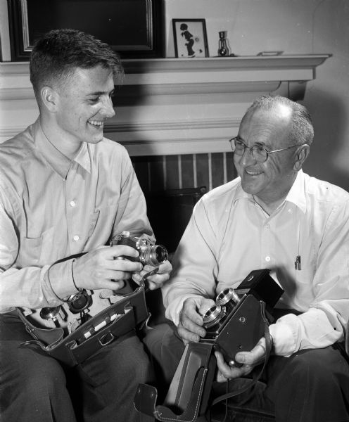 R. Glenn Weiss is shown with the eldest of his five children, Peter, age 22. They are looking at camera equipment acquired when Peter was stationed with the U.S. Army in Newfoundland.