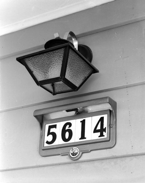 This house in the 1956 Parade of Homes in Meadowood with its illuminated device for showing the house numbers has been wired to the exact standards of the Madison Area Adequate Wiring Bureau. Indication of the code appears in the Madison Area Adequate Wiring Bureau symbol under the house numbers.