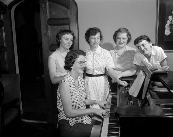 Team workers who attended the training institute for summer church schools of the Episcopal Church gather around the piano at St. Francis Episcopal Student Center. Sitting at the piano is Amy Weston of Florence, SC. Standing are Kathryn Arndt of Ann Arbor, MI; Susan Brady of Ripon, WI; Barbara Brand of Roseburg, OR; and Patricia Connell of Milwaukee. The girls are college students.