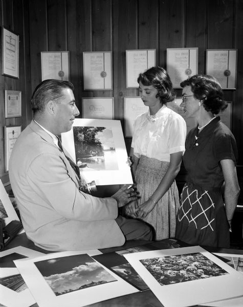 Richard W. Vesey of 1310 Jewel Court, editorial staff member and photographer of The "Wisconsin State Journal", is one of the featured speakers at the 24th annual convention of Theta Sigma Phi, honorary professional journalism sorority. He shows some of his photographic prints to two Theta Sigma Phi alumnae, Miss Helen Klieforth, 2702 Sommers Avenue, public relations director of the United Community Chest in Madison and Mrs. L.M. (Dorothy) Haines, 1442 Morrison Street, editor of the "East Side News."