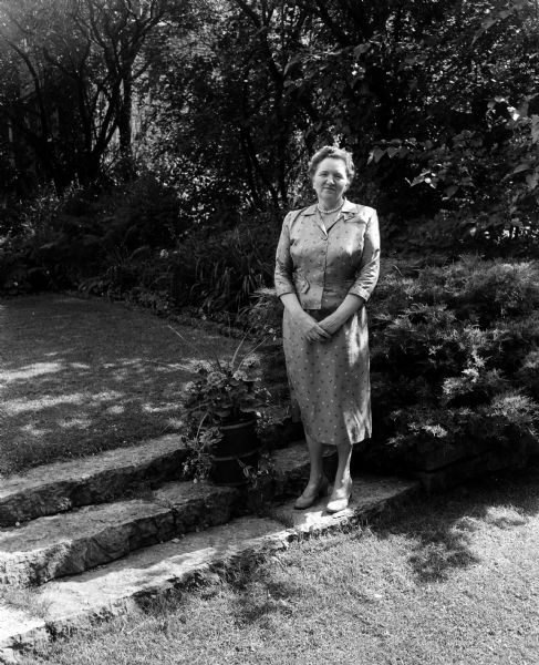 Mrs. Carroll V. Sweet is shown in the garden at her home at 163 North Prospect Avenue. She is one of ten hostesses for the third annual home and garden benefit tour sponsored by the Attic Angel Home, 102 East Gorham Street.