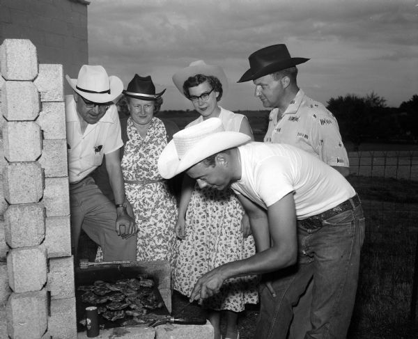 Will Holmes of Syene Road cooks meat for two Lions Club rodeo committee members and their wives. Left to right are G.I. Wallace, 2731 Mason Street; Mrs. (Arlene) Wallace; Mrs. Kenneth (Lois) Sixel, 606 Gately Terrace, and Mr. Sixel.